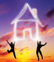 Happy couple jump and make a house symbol of light. Dreaming about new home, mortgage, new life together. Sunset sky